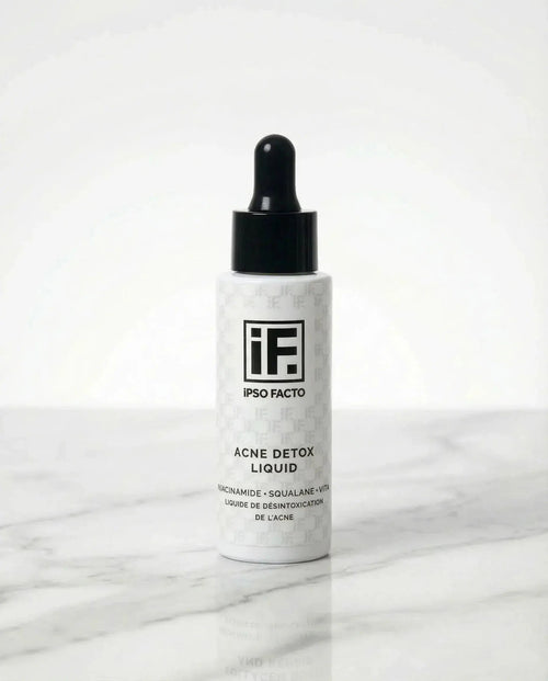Acne Detox Liquid serum bottle with dropper on white marble background, skincare product