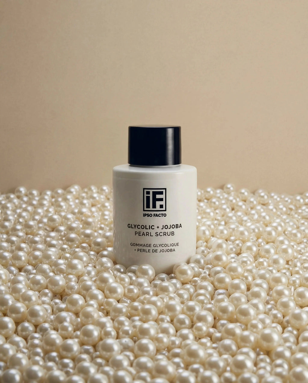 Glycolic and jojoba pearl scrub bottle surrounded by white pearls on beige background