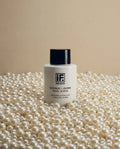 Glycolic and jojoba pearl scrub bottle surrounded by white pearls on beige background
