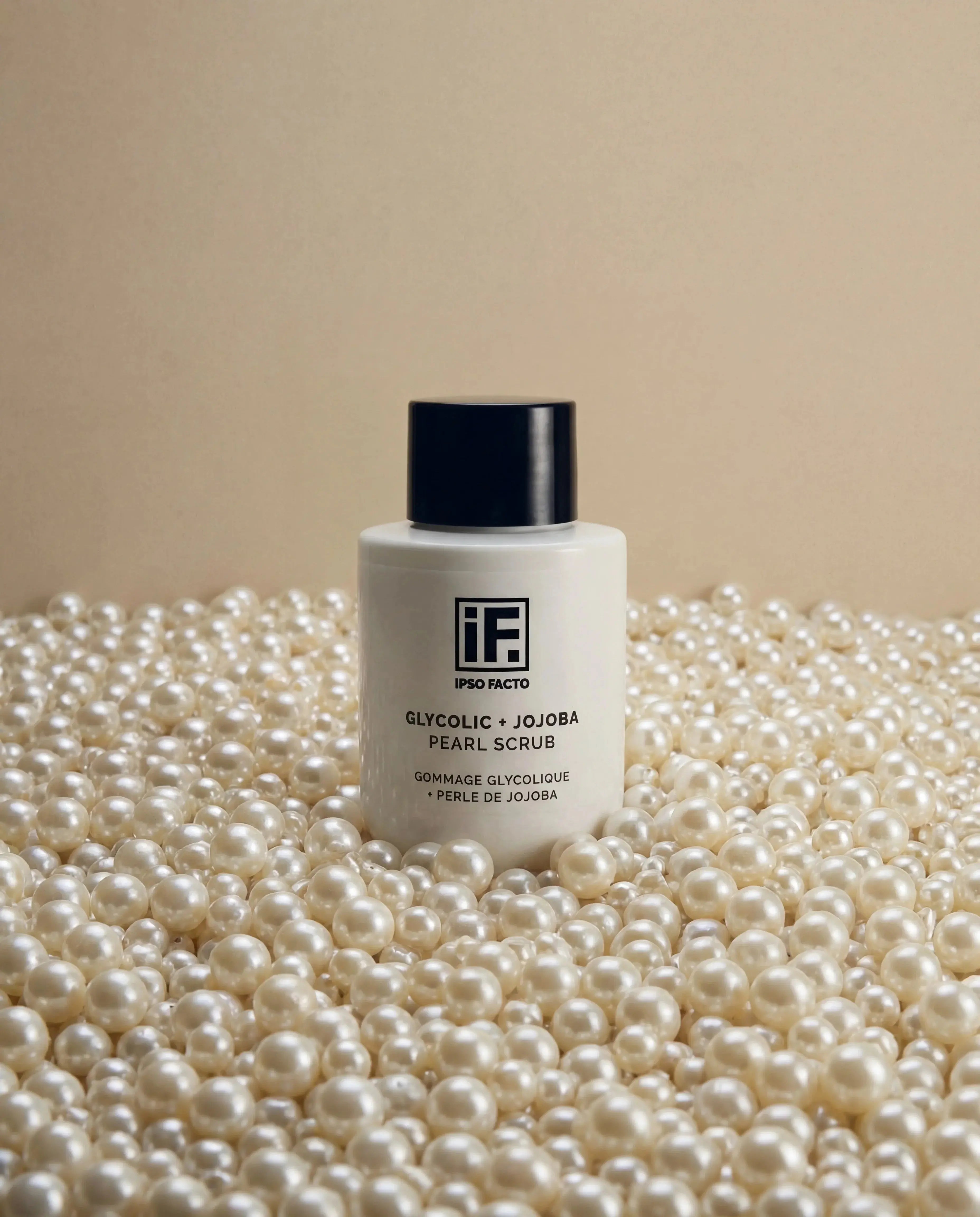 Glycolic and jojoba pearl scrub bottle surrounded by white pearls on beige background