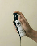 Hand holding a detox purifying cleanser bottle with black charcoal liquid flowing down