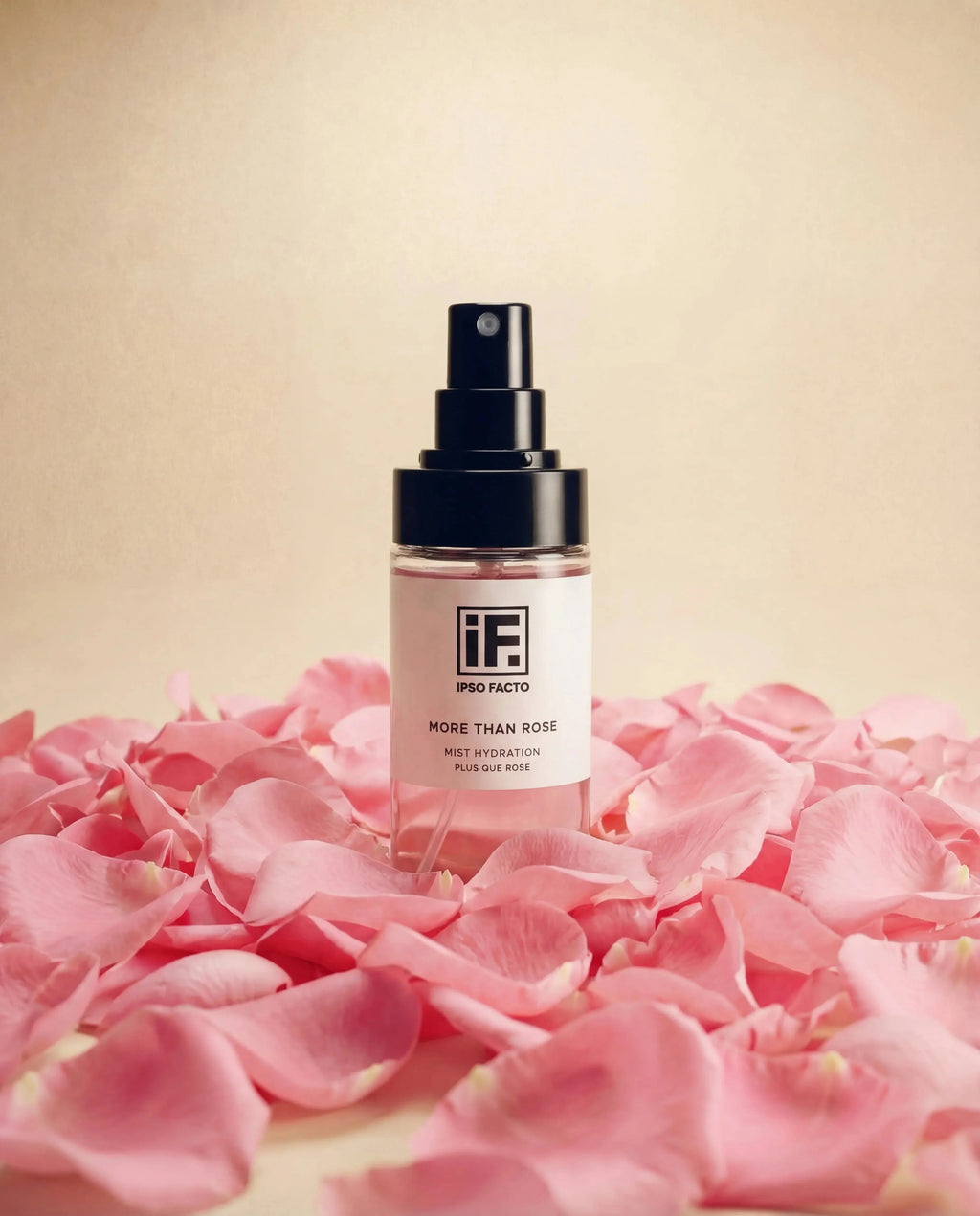 Hydrating facial mist spray bottle surrounded by pink rose petals on a neutral background