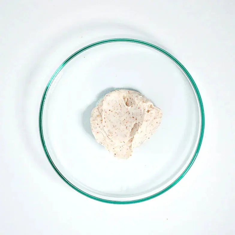 Creamy rosehip peel exfoliant with visible natural grains in a clear glass dish