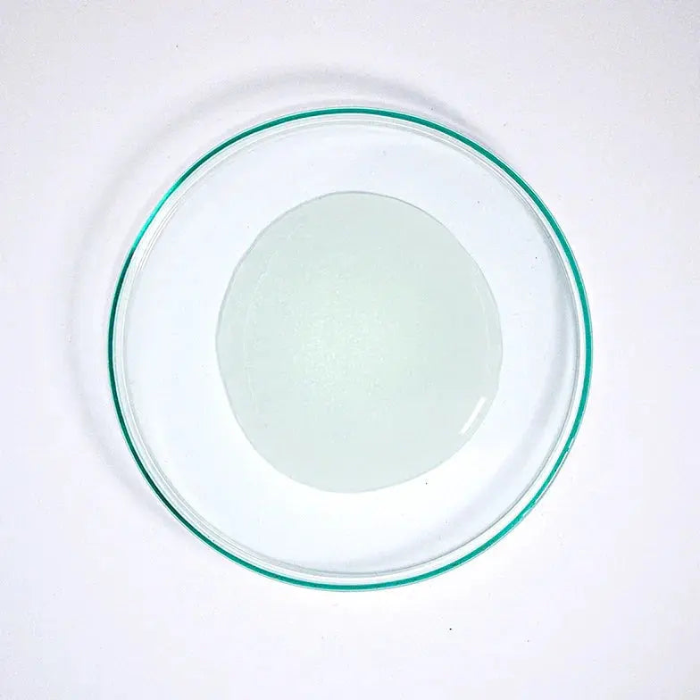 Clear glycolic acid facial scrub gel in a glass dish on a white background